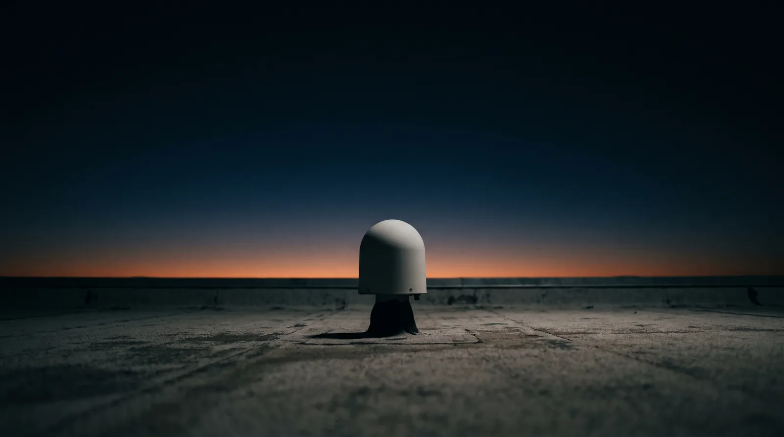 Antena de sincronización sobre una azotea de concreto contra el cielo del amanecer
